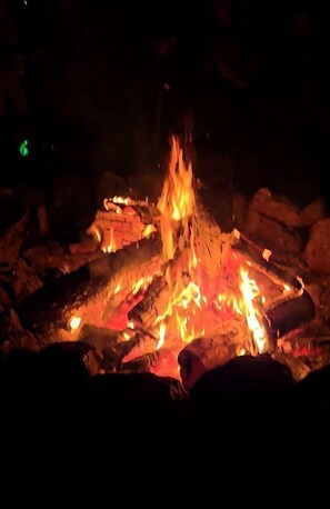 Un feu de camp avec des bûches et des braises, entouré de rochers.