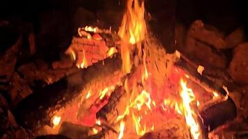 A campfire with logs and embers, surrounded by rocks.