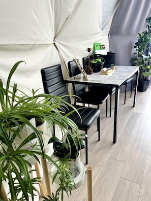 A dining area with a table, chairs, and potted plants.