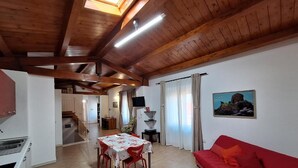 Une cuisine spacieuse avec un coin repas, un canapé rouge et un tableau accroché au mur.