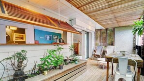 Een moderne buiten eethoek met een houten terras, een tafel met stoelen en potplanten.