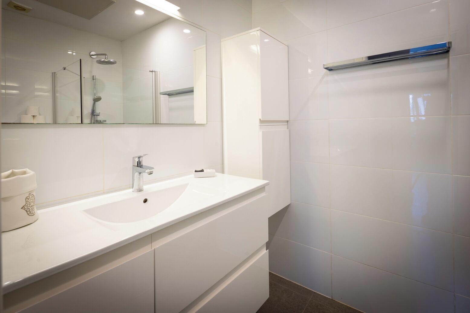 Une salle de bain moderne avec un lavabo blanc, un miroir et une douche.