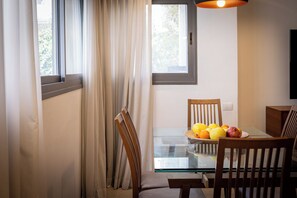A dining area with a glass table, wooden chairs, and a fruit bowl. - MAMAD - Chic and Comfort stay on Iconic (Tel Aviv)