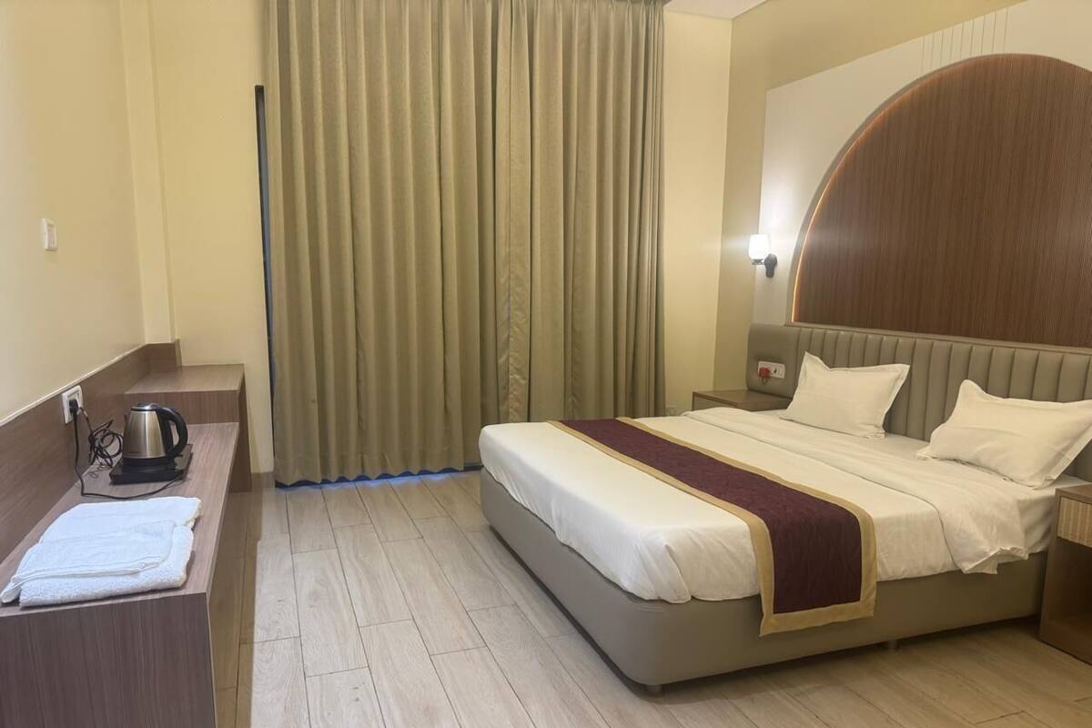 A hotel room with a bed, bedside table, and curtains.