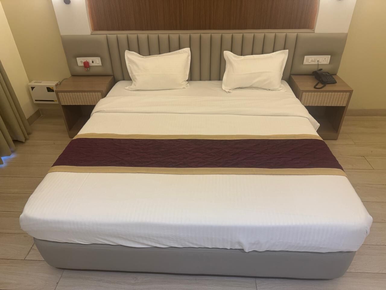 Una cama grande con cabecera, dos mesitas de noche y un teléfono sobre una de ellas.