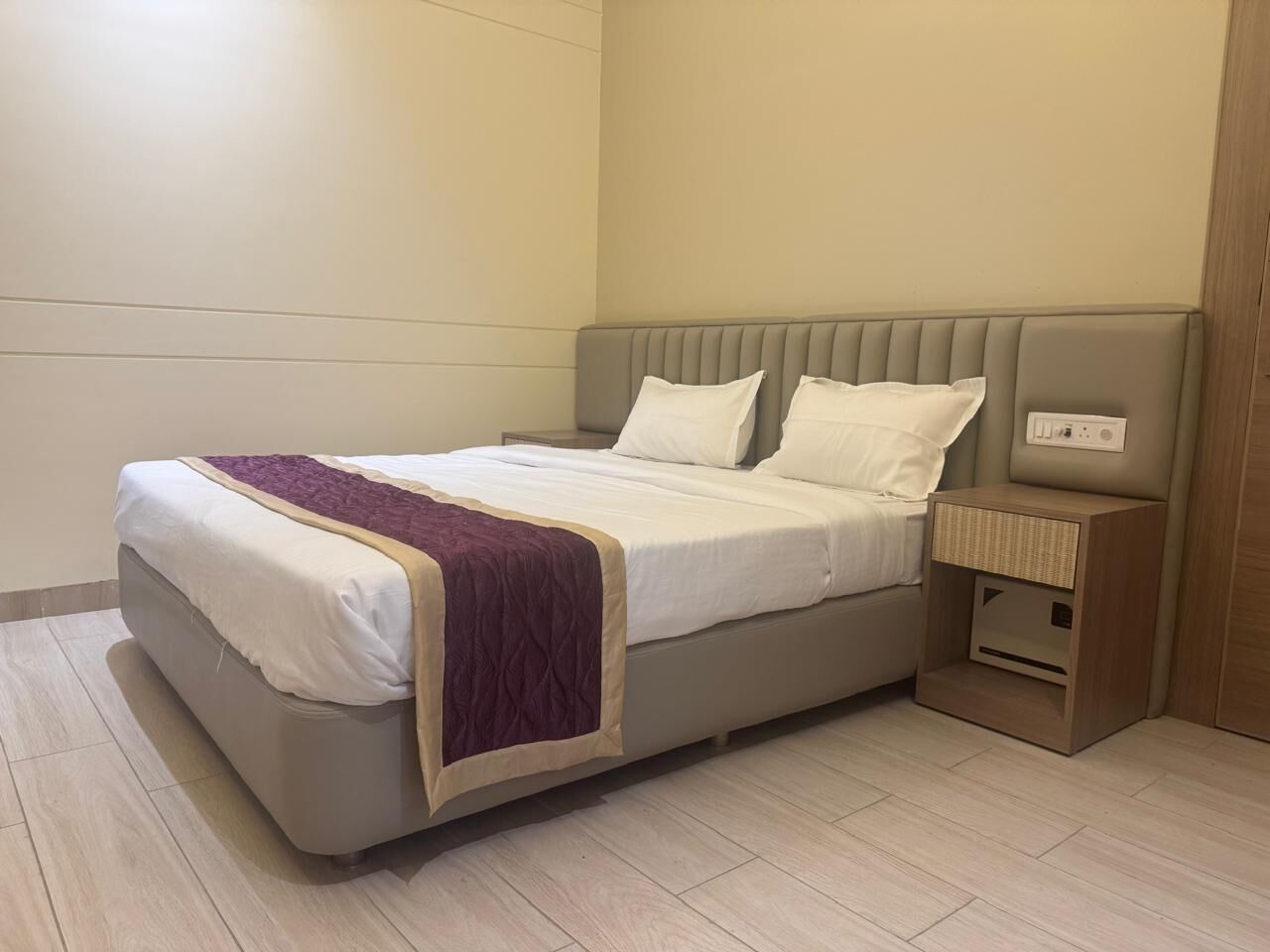 A neatly arranged bedroom with a bed, bedside tables, and a nightstand.