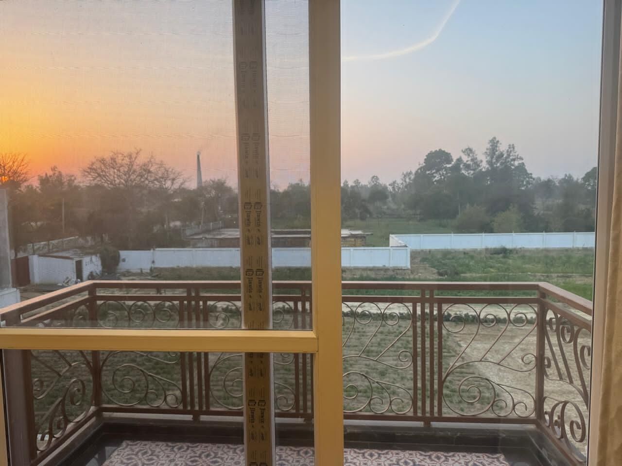 A balcony with a metal railing and a view of a landscape during sunset.