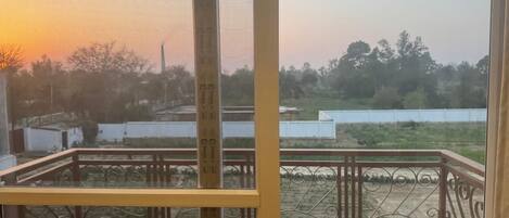 A balcony with a metal railing and a view of a landscape during sunset.