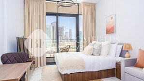 Habitación de hotel con una cama grande, una mesa de comedor, una silla, un sofá y vistas a la ciudad.