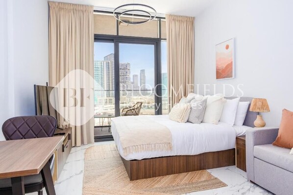 A hotel room with a large bed, a dining table, a chair, a sofa, and a view of the cityscape. - Bloomfields Cozy Stu in Al Maryah (Abu Dhabi)