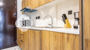 Una cocina moderna con armarios de madera, una encimera blanca, una cafetera y un bloque para cuchillos.