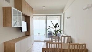 A modern dining area with wooden furniture, a built-in TV, and a view of the outdoors. - SE207 - Stunning Two-Room Apartment Overlooking the Sea (Senigallia)