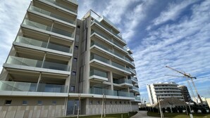 A multi-story hotel with balconies, a central stairwell, and a construction crane in the background. - SE207 - Stunning Two-Room Apartment Overlooking the Sea (Senigallia)