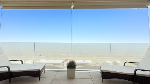 A balcony with two wicker chairs, a potted plant, and a view of a desert landscape. - SE207 - Stunning Two-Room Apartment Overlooking the Sea (Senigallia)