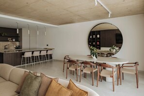 A modern kitchen with a bar area, a dining table with chairs, and a large round mirror. - High-floor views, hot tub & sauna | AZ13 (Sliema)