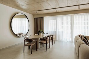 A modern living room with a round dining table, chairs, a large mirror, and a sofa. - High-floor views, hot tub & sauna | AZ13 (Sliema)