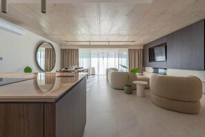 Ein modernes Wohnzimmer mit einer zentralen Insel, einer Sofagarnitur, einem an der Wand montierten Fernseher und einem großen Fenster mit Vorhängen.
