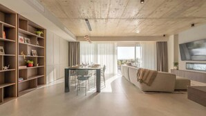 Una sala de estar moderna con comedor, un sofá y un televisor montado en la pared.