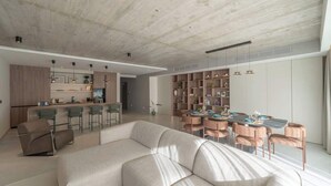 A modern living room with a sofa, a dining table with chairs, and a kitchen area with bar stools. - Valletta views, hot tub, sauna, ferries | AZ12 (Sliema)