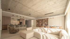 A modern living space with a large L-shaped sectional sofa, a kitchen area with bar stools, and a dining area with a table and chairs. - Valletta views, hot tub, sauna, ferries | AZ12 (Sliema)