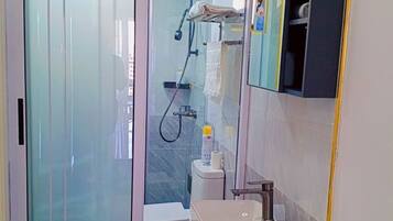 Et moderne badeværelse med en glasbrusekabine, en hvid vask og et mørkt toiletbord.
