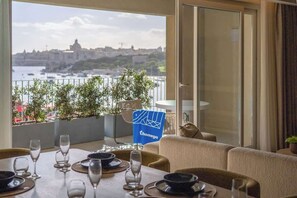 Un coin repas avec une table dressée pour quatre personnes, offrant une vue panoramique sur la ville et l’eau.