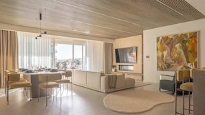Ein modernes Wohnzimmer mit Essbereich, einem großen Gemälde an der Wand und einem Flachbildfernseher.