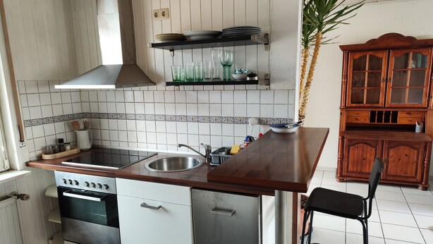 A kitchen with a stove, sink, and a wooden cabinet. - Apartment 'Ferienunterkunft Göhlich' with Balcony and Wi-Fi (Maintal)
