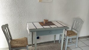A dining area with a table and two chairs, a rug, and a painting on the wall. - Apartment 'Ferienunterkunft Göhlich' with Balcony and Wi-Fi (Maintal)