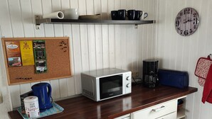A compact kitchen with a microwave, coffee maker, and a corkboard with notices. - Apartment 'Ferienunterkunft Göhlich' with Balcony and Wi-Fi (Maintal)