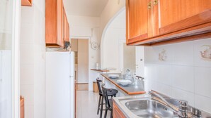A kitchen with wooden cabinets, a white refrigerator, a sink, and a dining area with chairs. - Lovely apartment in Rapallo with WiFi (Rapallo)
