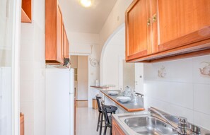A kitchen with wooden cabinets, a white refrigerator, a sink, and a dining area with chairs. - Lovely apartment in Rapallo with WiFi (Rapallo)