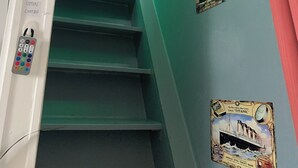 Una escalera con peldaños verdes, un aplique en la pared y un cartel del Titanic.