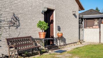 Een bakstenen gebouw met een bankje en bloempotten ervoor.