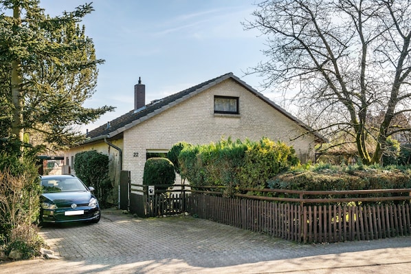 A two-story house with a brick exterior, a paved driveway, and a wooden fence.
