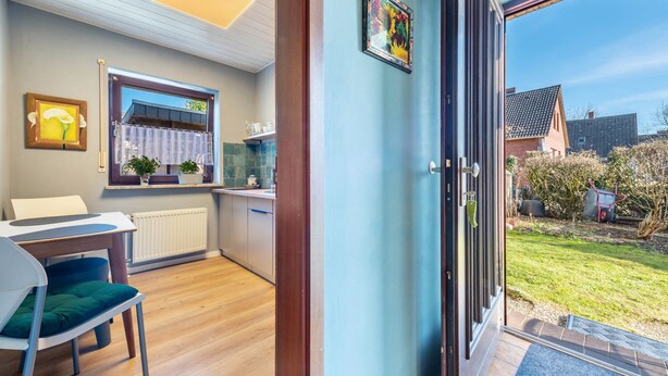 Eine moderne Küche mit Fenster, ein Essbereich mit Tisch und Stühlen sowie Blick auf den Garten.