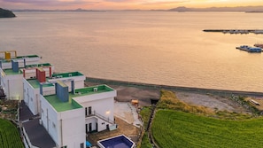 Un bâtiment situé sur la côte, doté d’une piscine sur le toit, d’un espace vert et offrant une vue sur la mer.