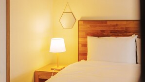 Habitación de hotel con cabecera de madera, lámpara de noche y almohada blanca.