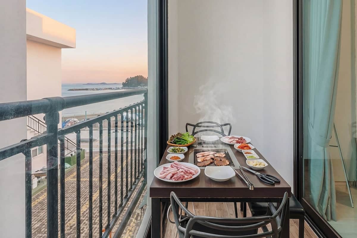 Un balcon avec une table dressée pour un repas, donnant sur une étendue d’eau.