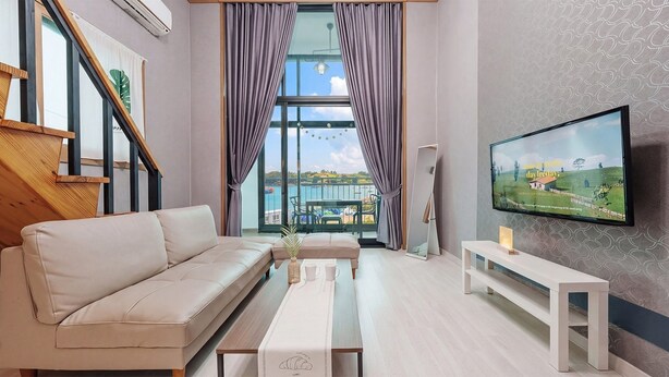 En moderne stue med sofa, sofabord, fjernsyn og en balkon med havudsigt.