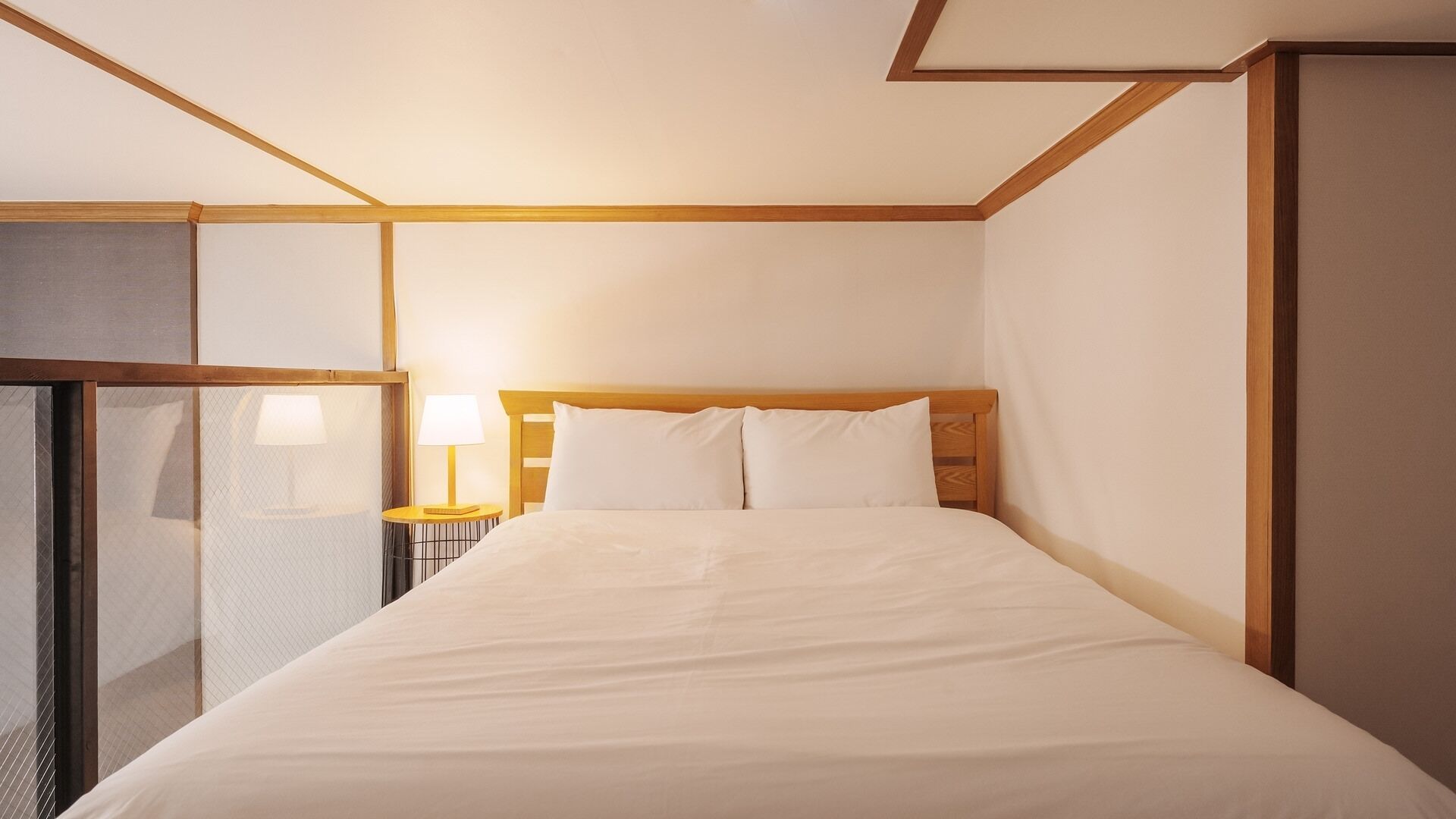 Una habitación de hotel con una cama, una mesita de noche con lámpara y una ventana con persianas.