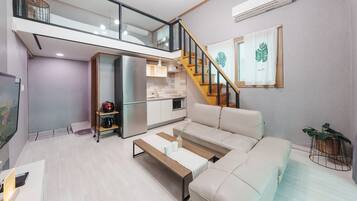 Un apartamento moderno con sala de estar, cocina y una escalera que conduce a un piso superior.
