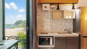 Cocina compacta con microondas, pileta y alacena, con vista a un paisaje pintoresco.