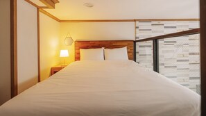 A hotel room with a bed, a nightstand with a lamp, a wooden headboard, and a window with a patterned view. - Yeosu The Haru Ocean View Pension (Yeosu)