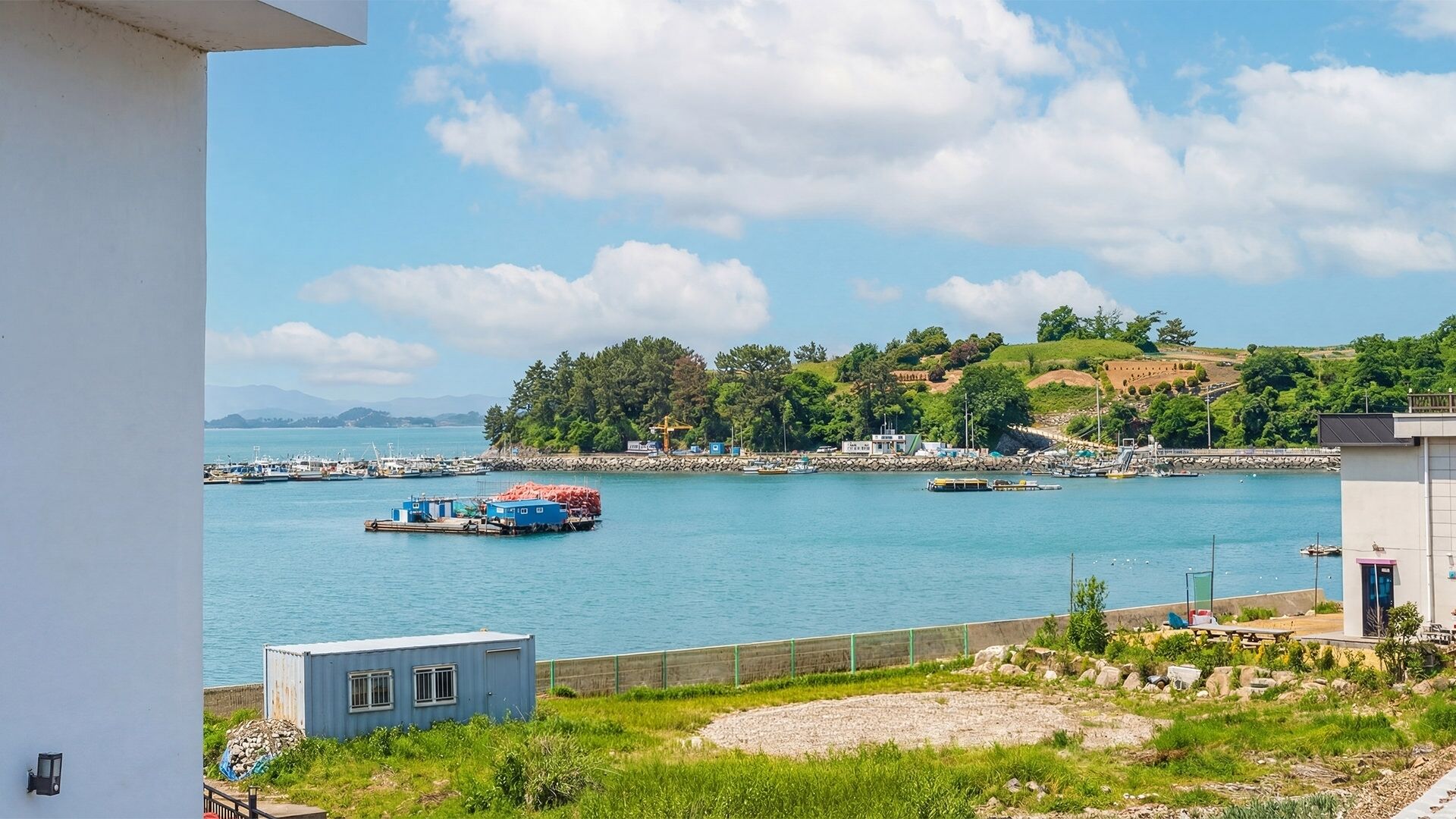 A coastal view with a marina, boats, and a small building.