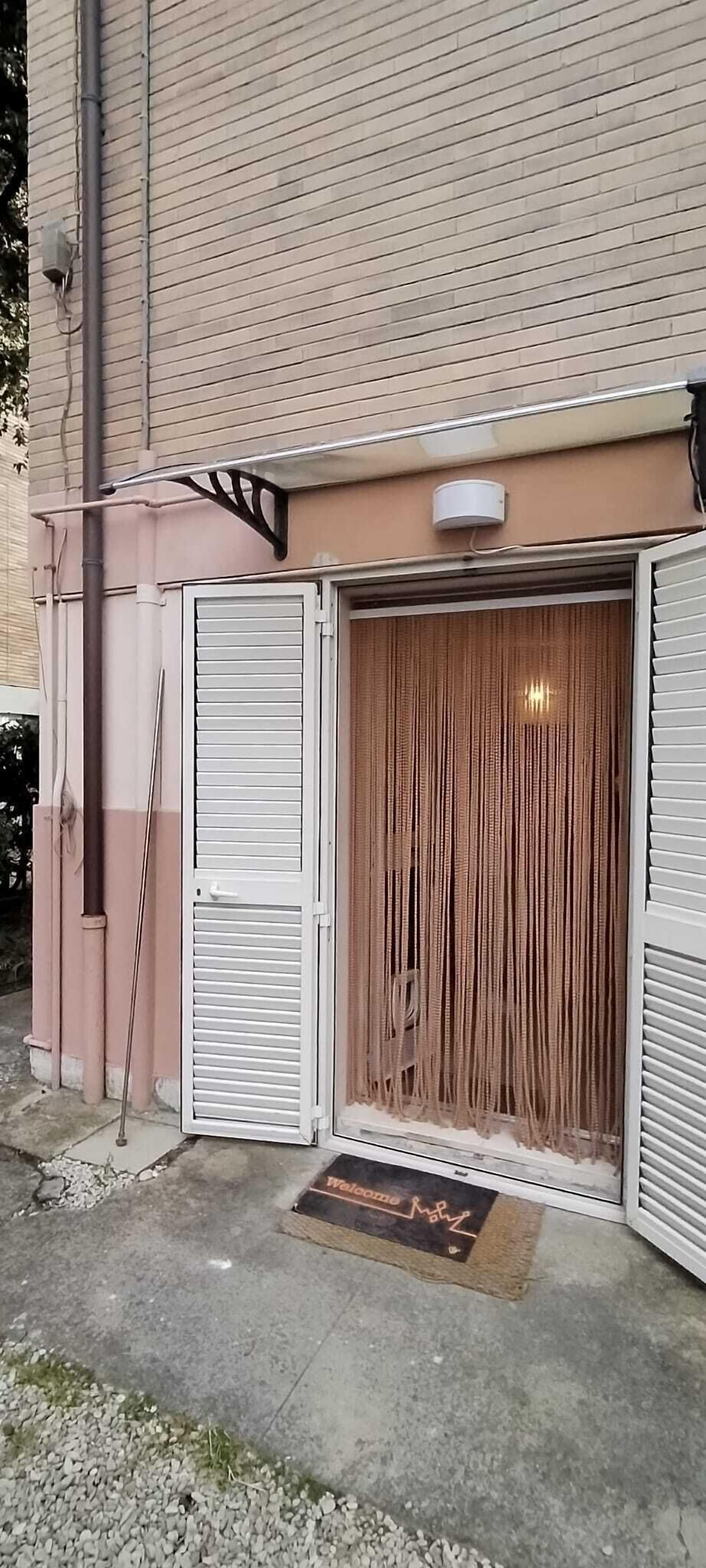 A building with a closed entrance, a welcome mat, and a security camera.
