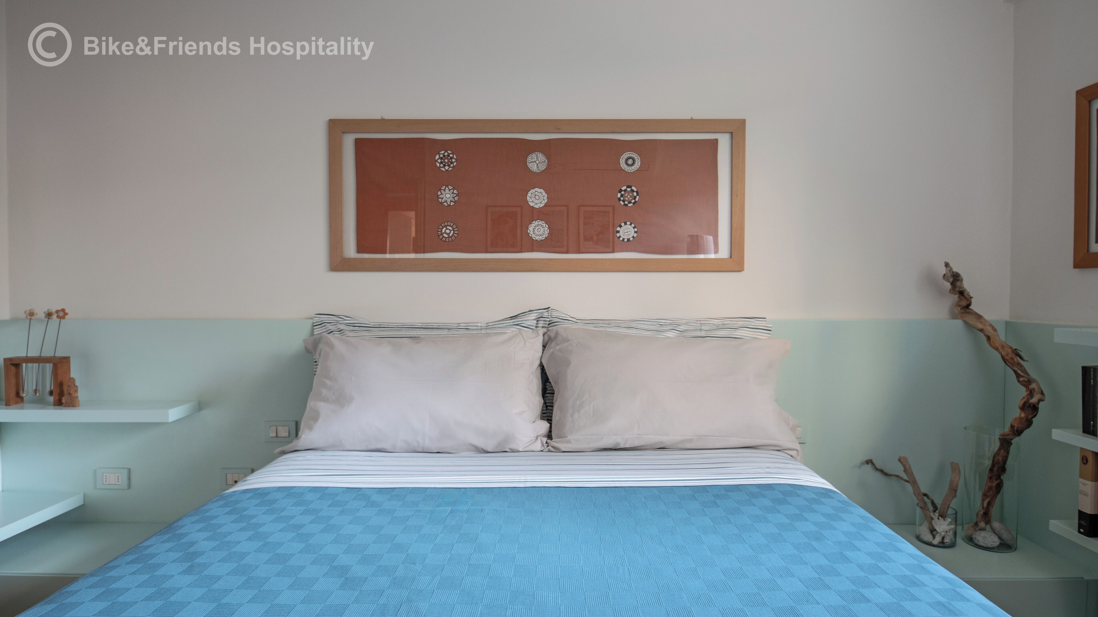 Un dormitorio con cama, almohadas, un reloj de pared y un adorno sobre la cama.