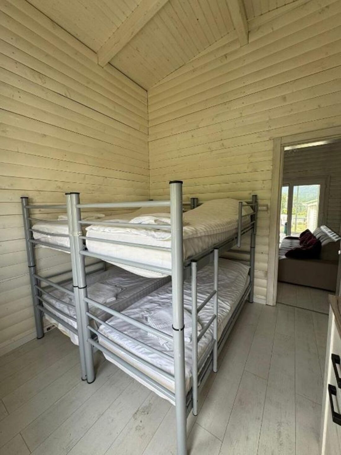 A bunk bed room with metal railings and a wooden ceiling.