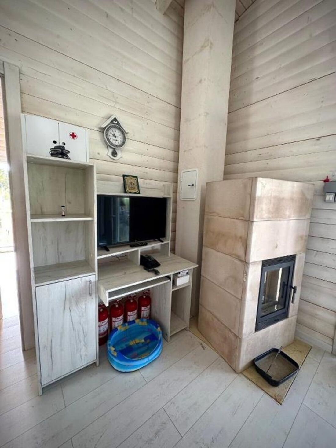 A compact living space with a built-in fireplace, a television, and a small shelf unit.
