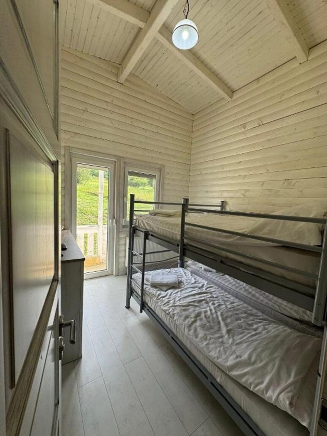 A dormitory room with bunk beds, a desk, and a window.